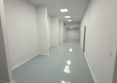 Long corridor with white walls, a white cove base and a glossy gray floor