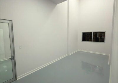 White room with a glass door, a small wall window and a white cove base along a gray floor