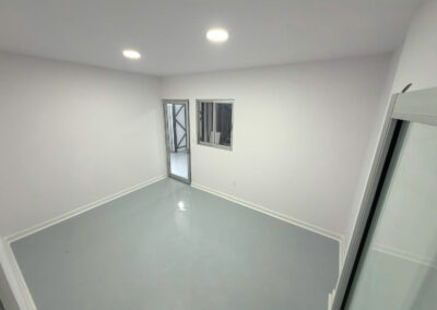 White room with a white cove base along a gray floor, a door and a window