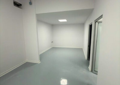 White room with an alcove, a white cove base along a gray floor and a door on the right